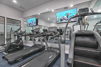 a gym with cardio equipment and flat screen televisions